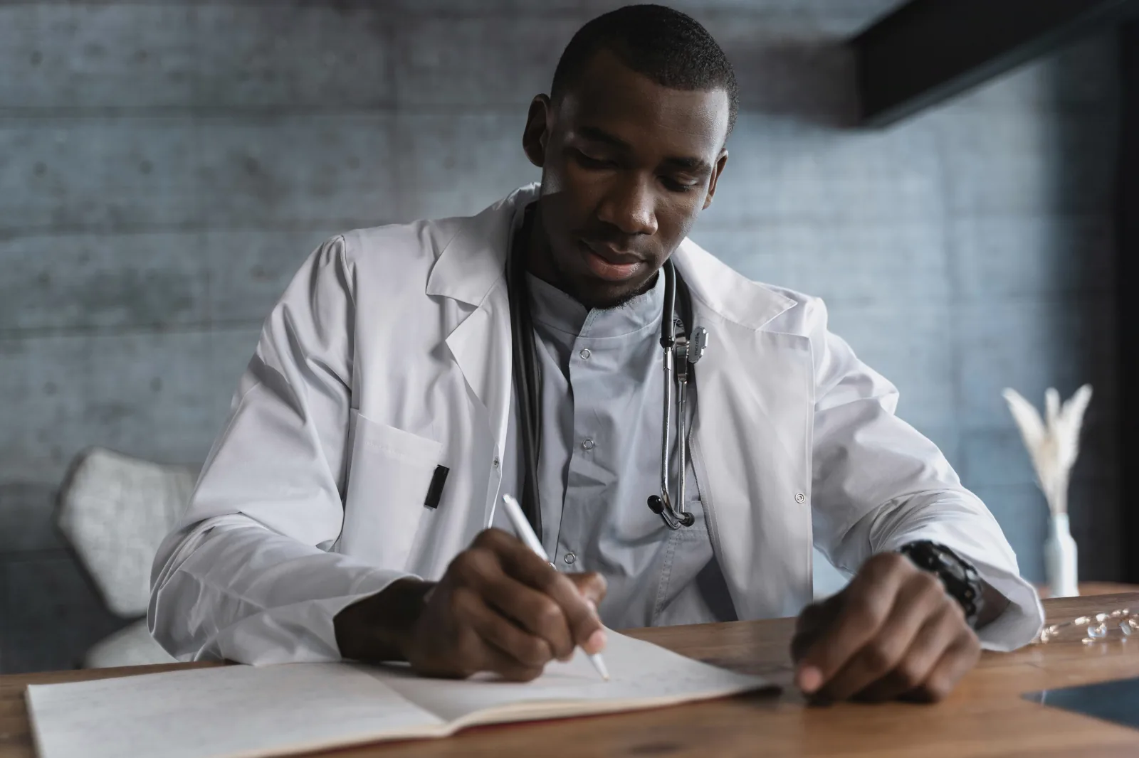 Doctor writing notes while reviewing a patient case.