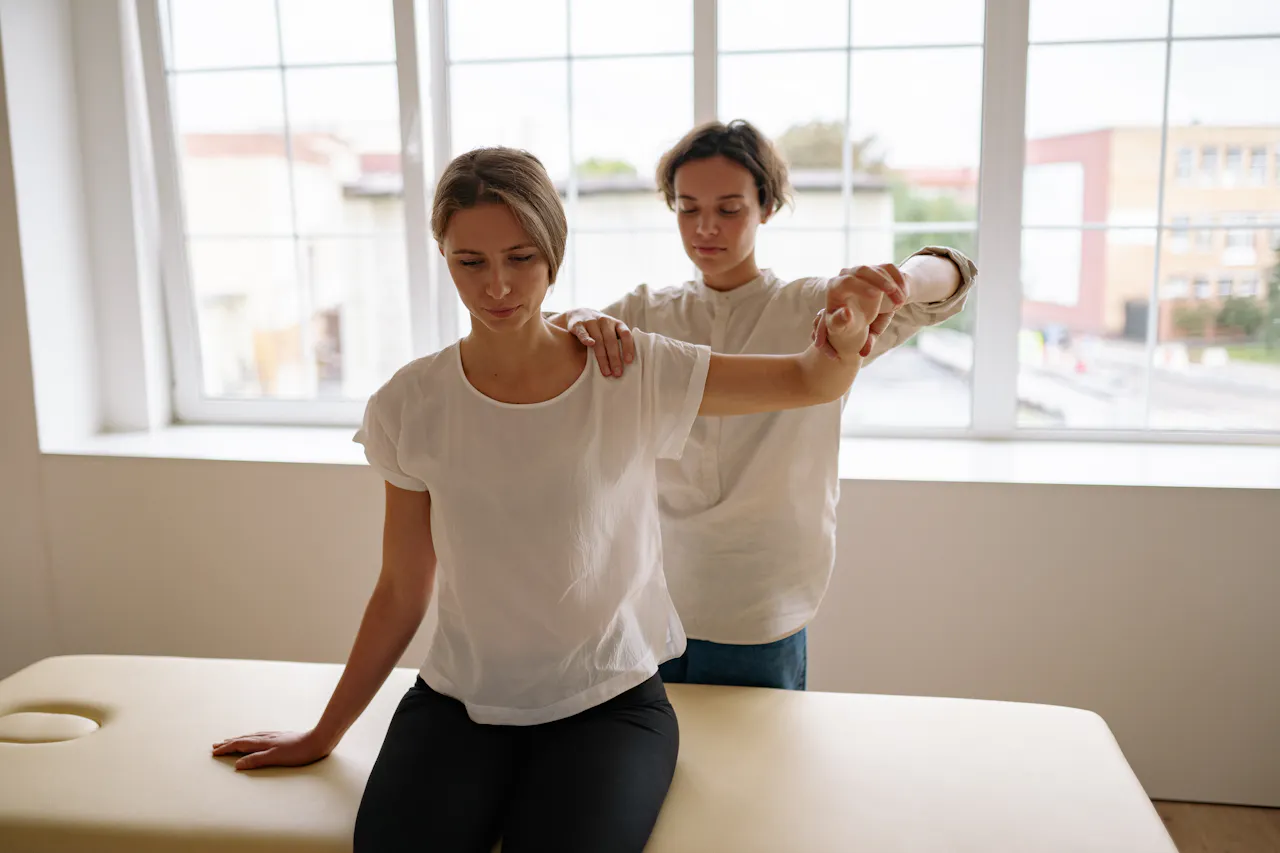 Physical therapist guiding shoulder rehabilitation in a bright treatment room.