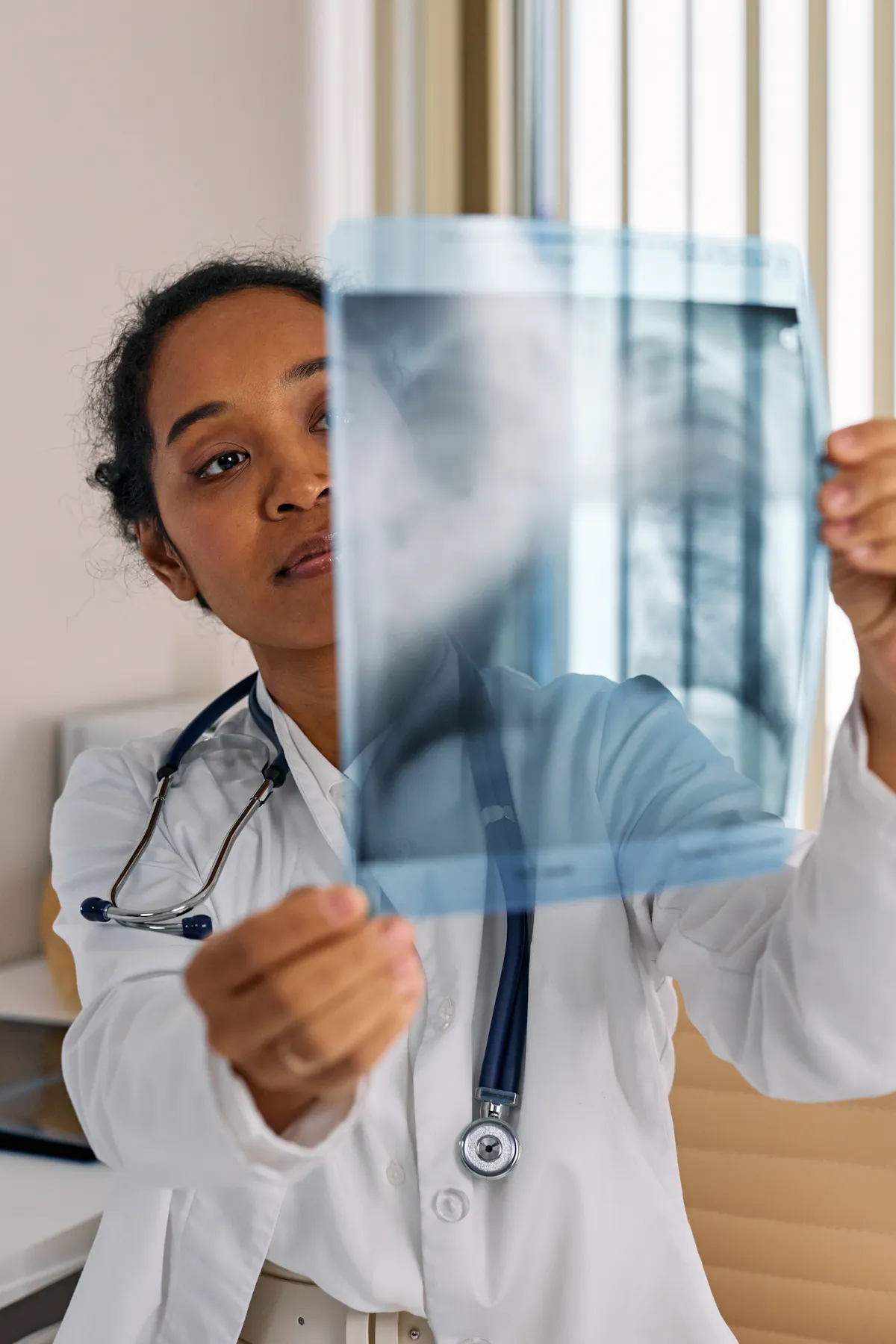 Doctor holding and reviewing an X-ray image in a clinic setting.